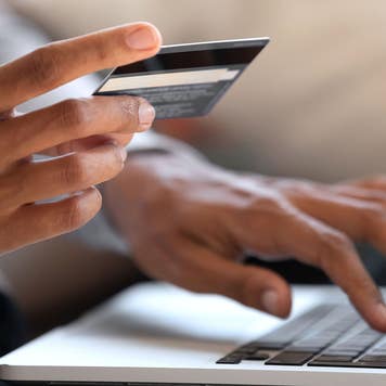 Woman holding a credit card while typing on a laptop