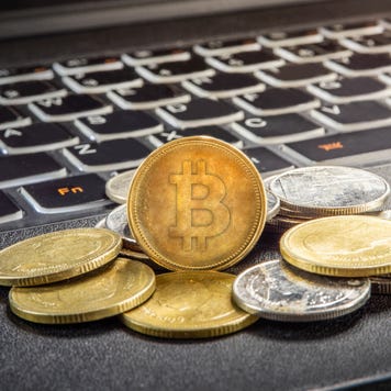 A pile of physical bitcoins on a laptop computer