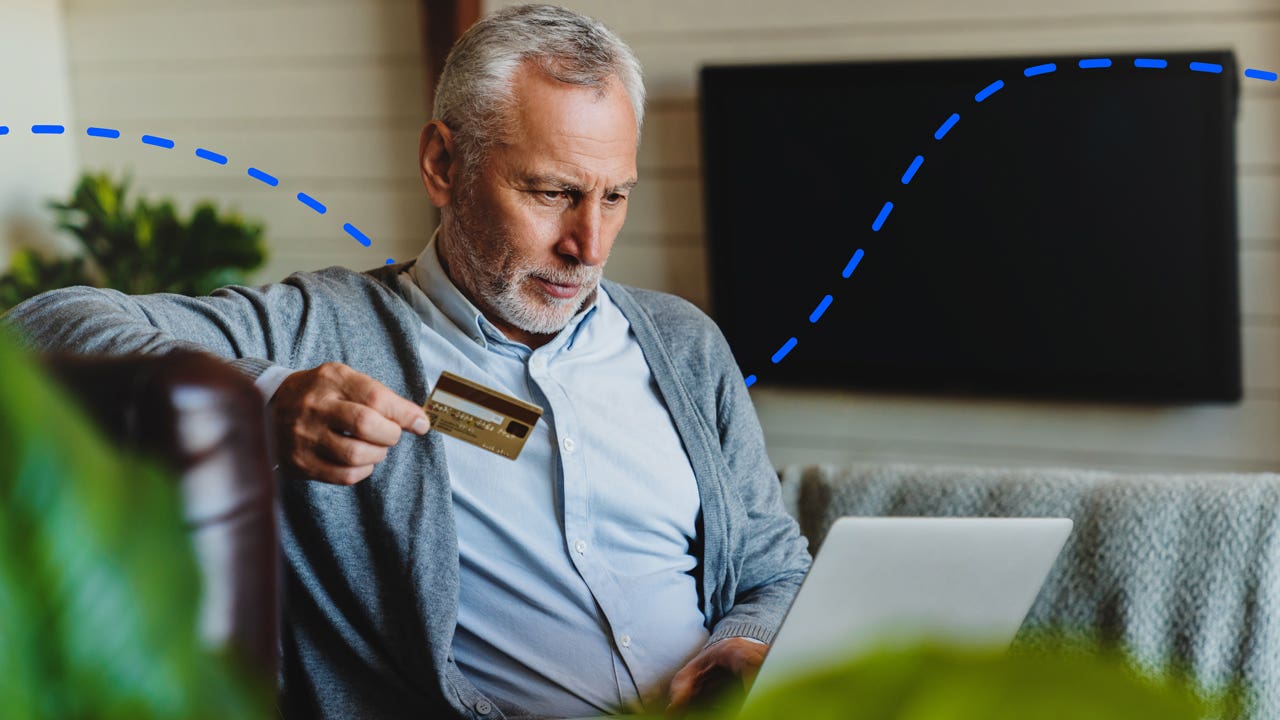 older person holding a card and on a computer