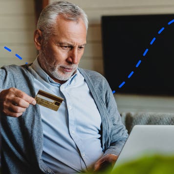 older person holding a card and on a computer