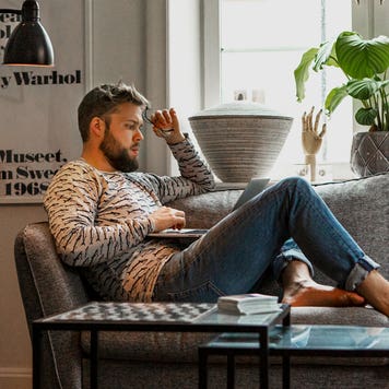young person sitting on their couch on their computer