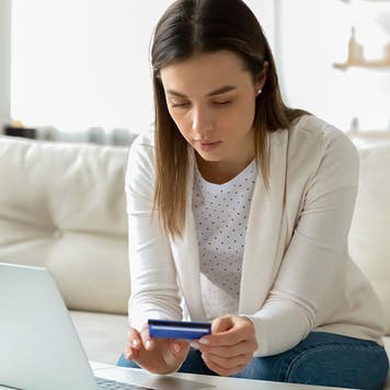 Focused young woman entering banking credit card information in computer application, making household payments online, booking flight tickets or hotel, purchasing goods or confirming transaction.