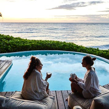 two women sitting by a hotel pool