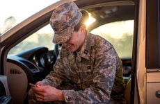 Female soldier sitting in car and using her phone