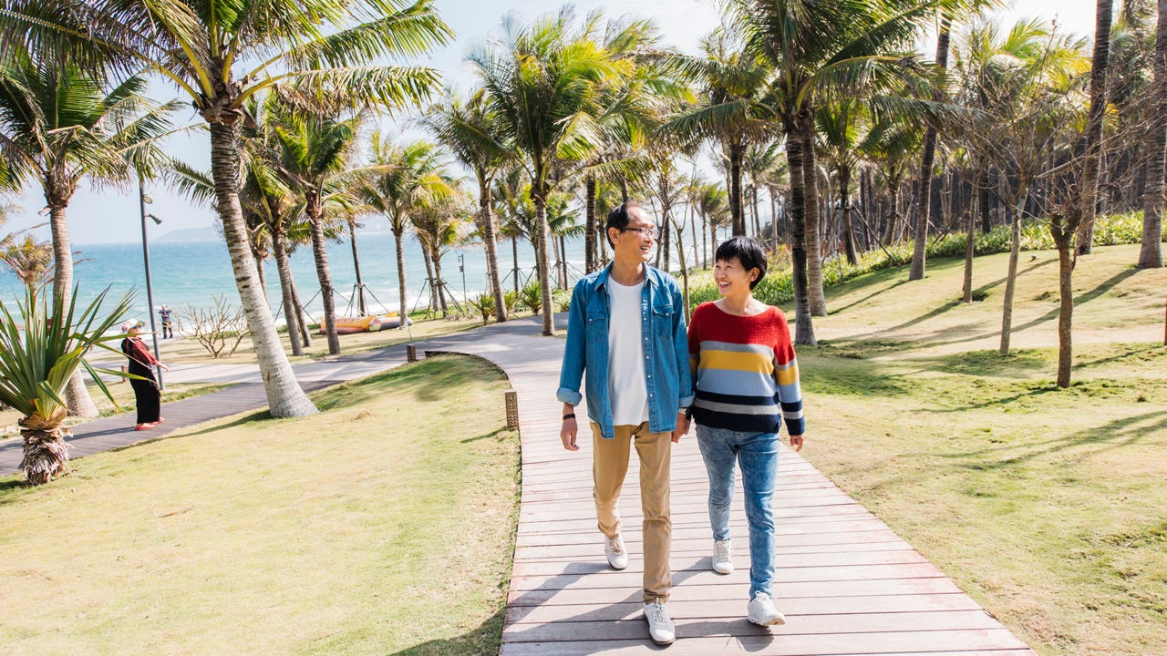 couple walking on path near ocean