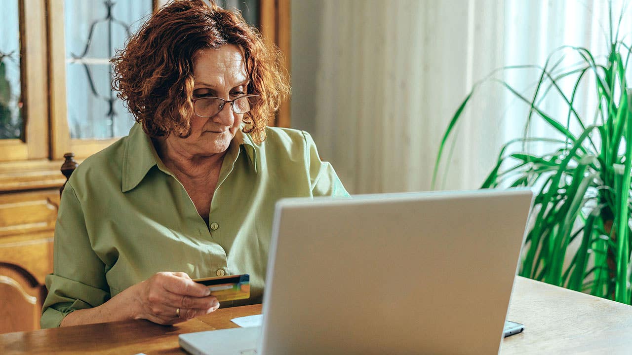 Senior woman using a laptop and a credit card at home
