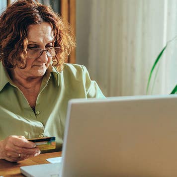 Senior woman using a laptop and a credit card at home