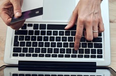 close up of woman's hand typing on a laptop and holding a credit card