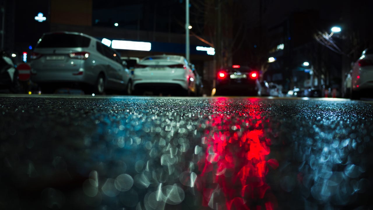 Abstract night city background with red stop lights reflection on wet asphalt