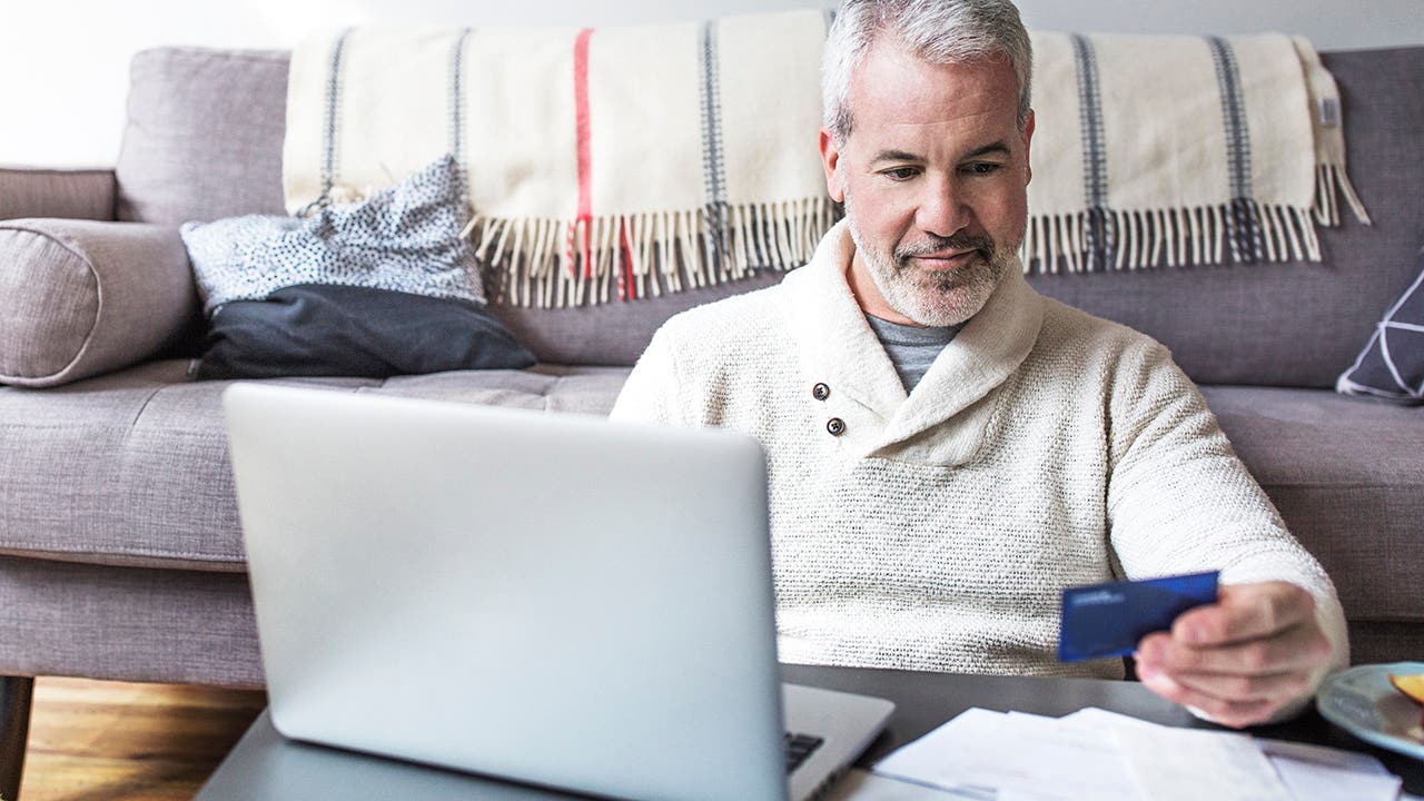 Senior man using a credit card at home