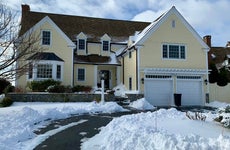 A pale yellow single-family with two-car garage in wintertime