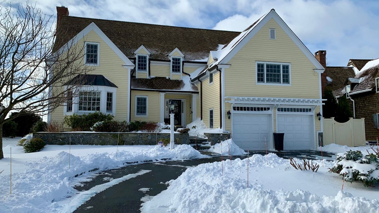 A pale yellow single-family with two-car garage in wintertime