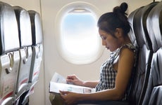 Woman rides on an airplane and reads a magazine
