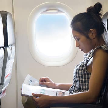 Woman rides on an airplane and reads a magazine