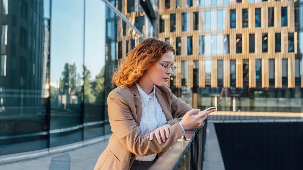 businesswoman using mobile phone leaning on railing