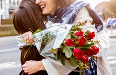 Women embracing partner with a bouquet of red roses