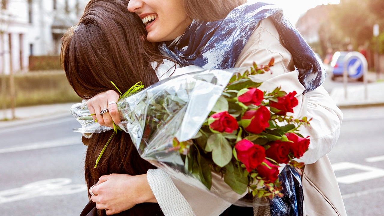 Women embracing partner with a bouquet of red roses
