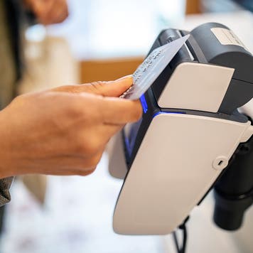 Woman using credit card for contactless payment at checkout