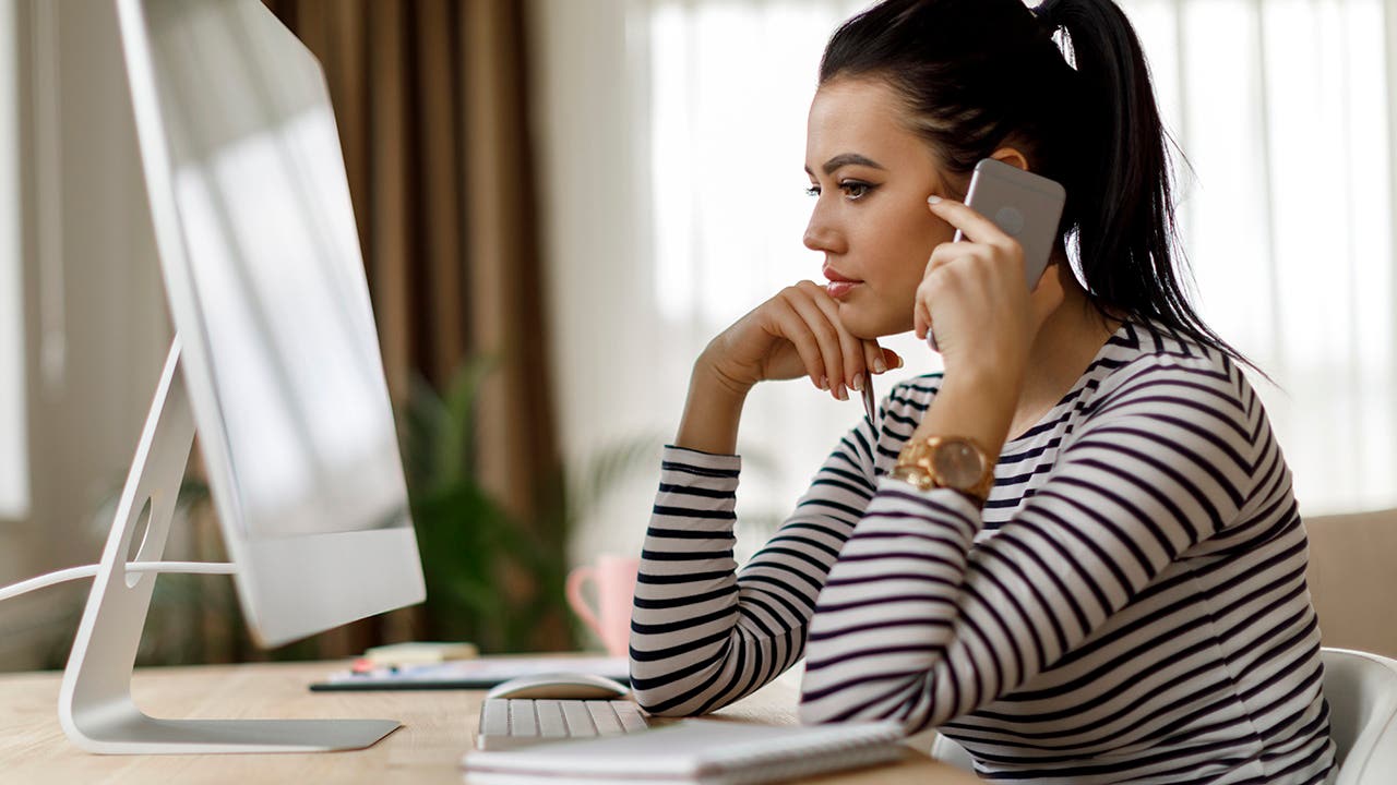 young woman looking at the computer and talking on the phone