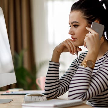 young woman looking at the computer and talking on the phone
