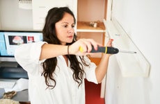 woman fixing a shelf at home with a screwdriver