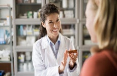 Pharmacist hands medication to a customer