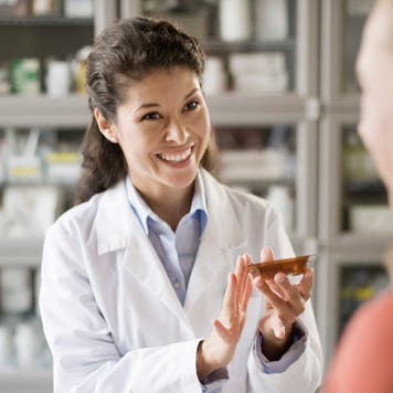 Pharmacist hands medication to a customer