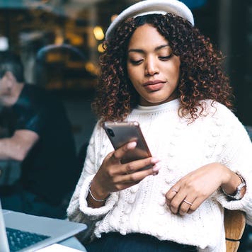 Woman sitting outside of restaurant looking at cell phone