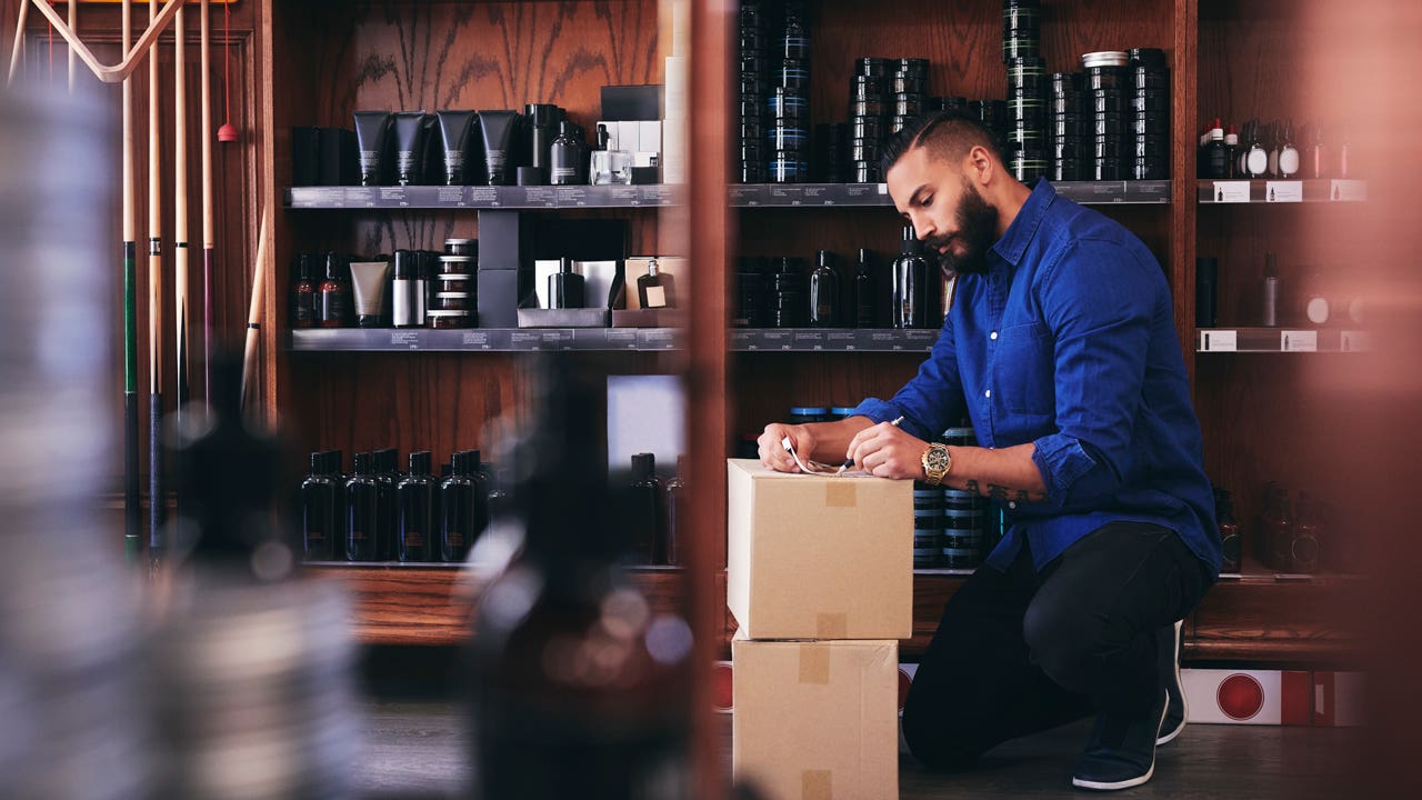 man kneeling in store and unpacking boxes