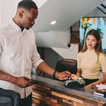 man using credit card at hotel reception desk