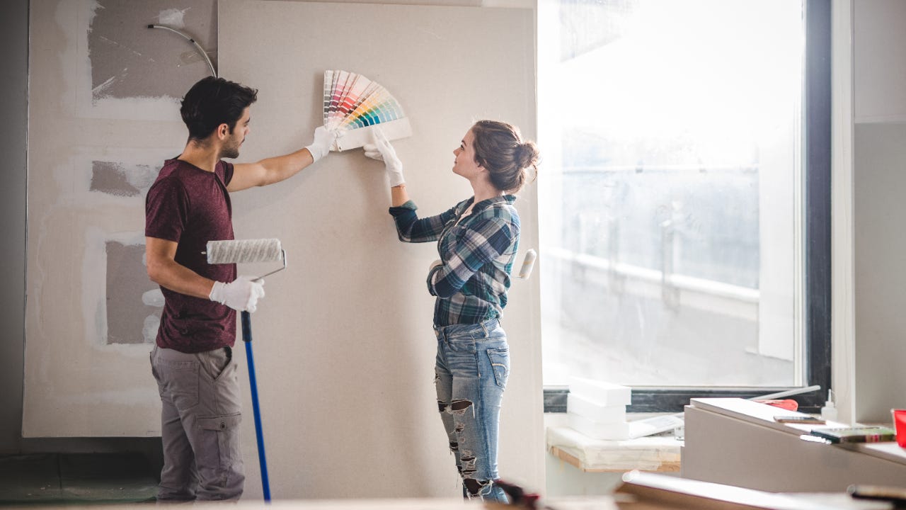 Young couple choosing the right color for their wall in new apartment.