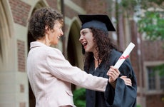 Mom and college graduate smile at graduation