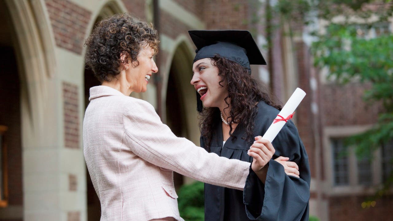 Mom and college graduate smile at graduation