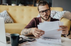 man working on his finances at home with laptop and papers