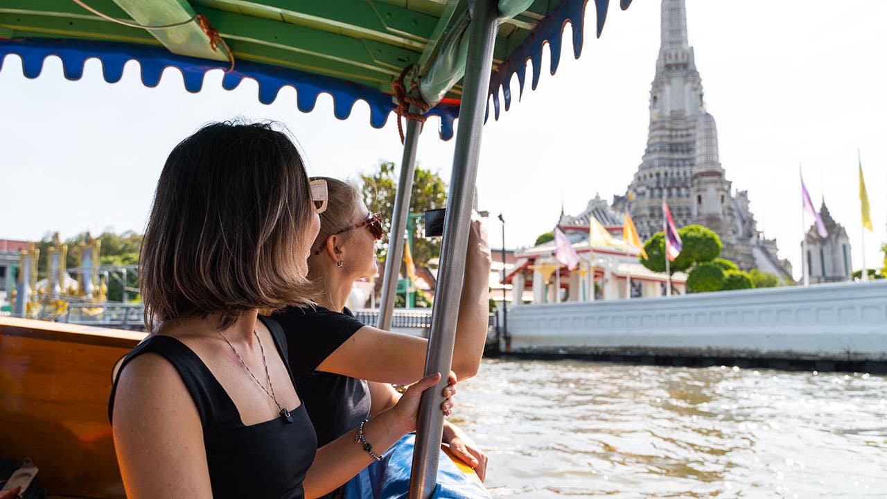 two women riding a boat in bangkok