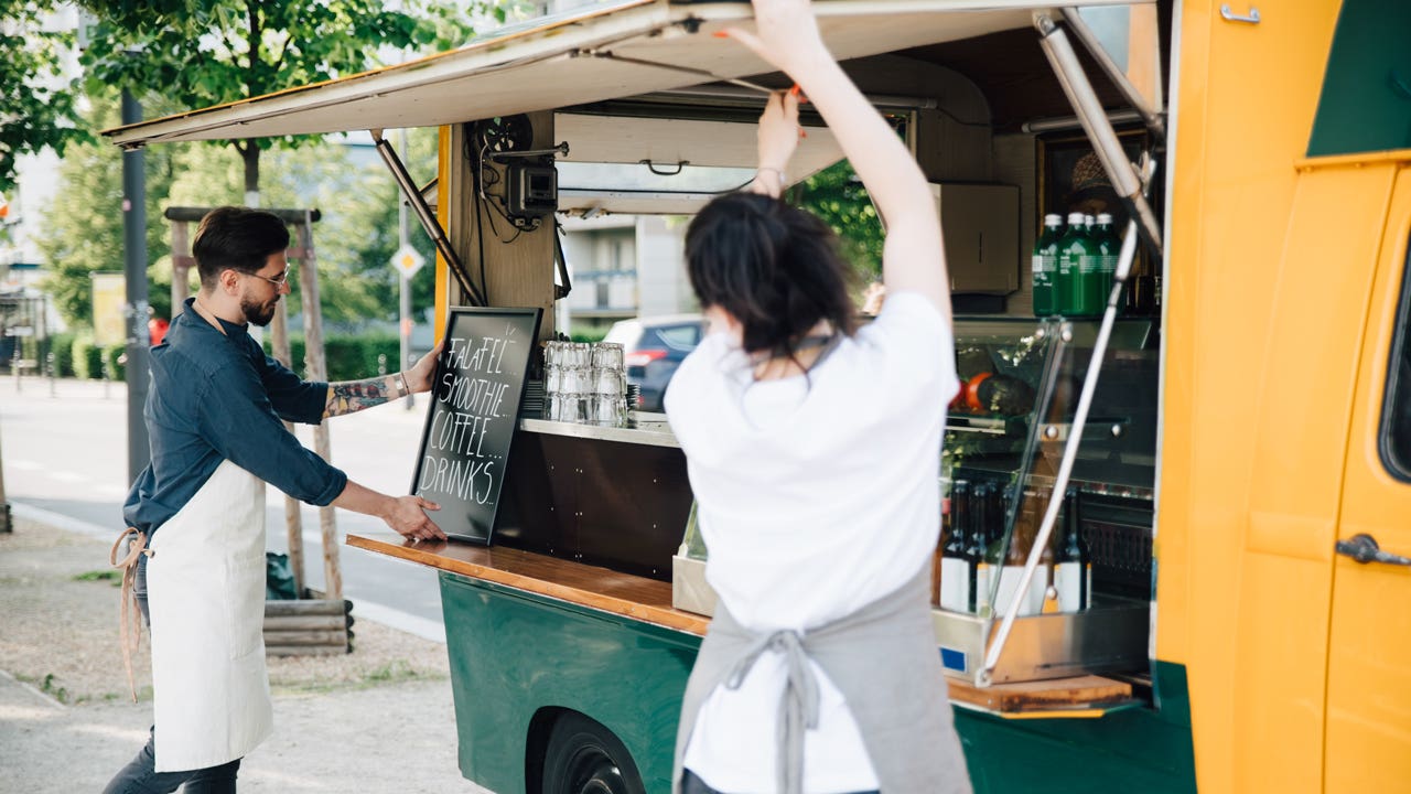 man and woman opening the side window of a food truck