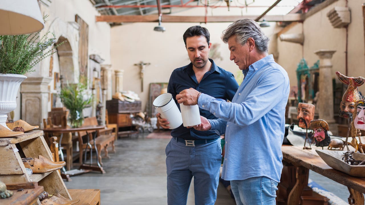 Owner of antique shop talking with customer in his store