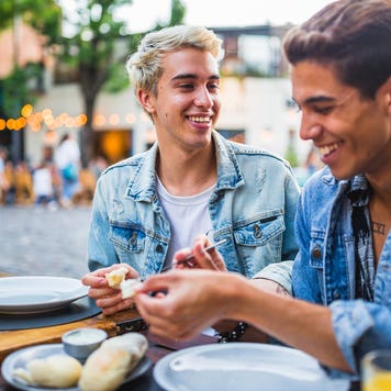 two men eating together at outdoor cafe