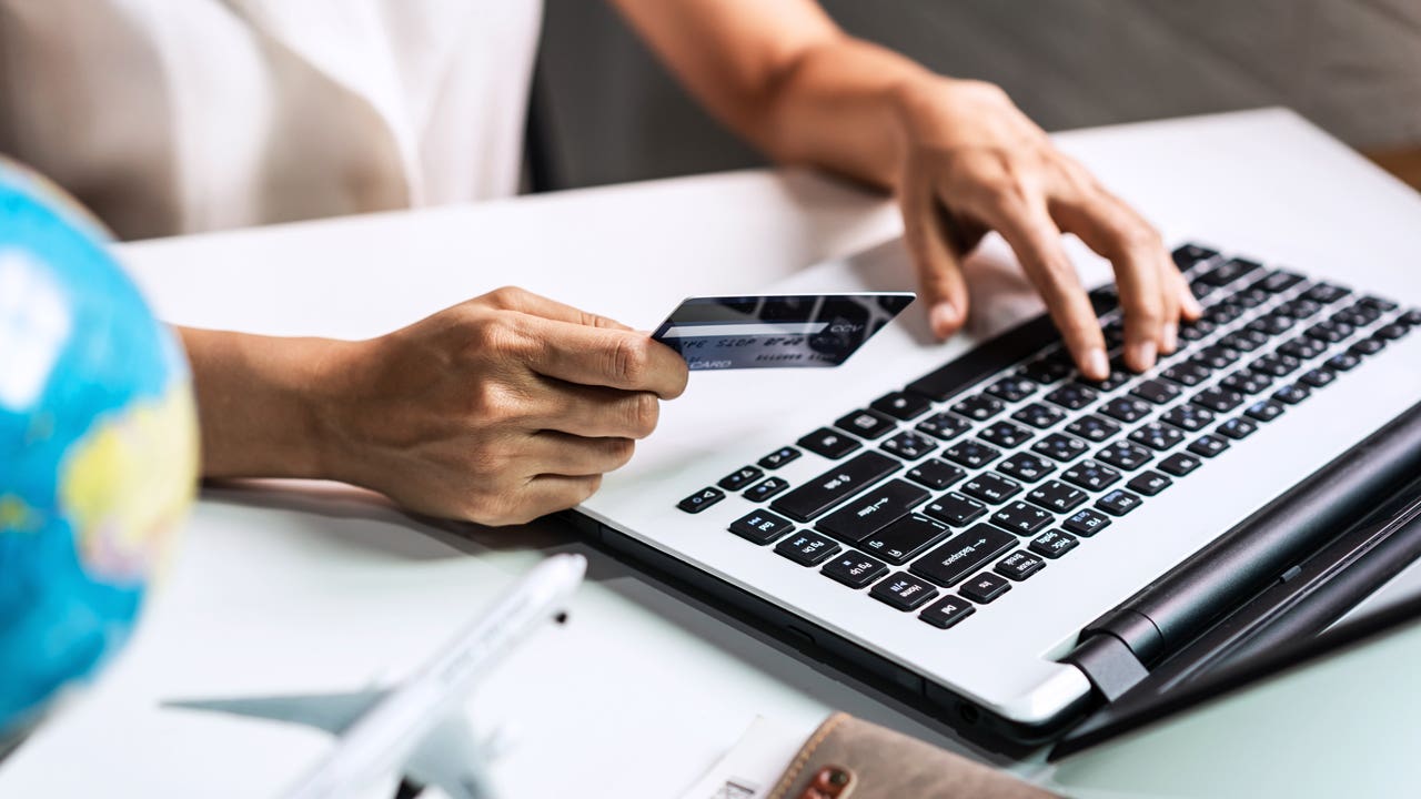 close up of woman's hands holding credit card and typing on laptop