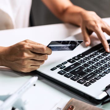 close up of woman's hands holding credit card and typing on laptop