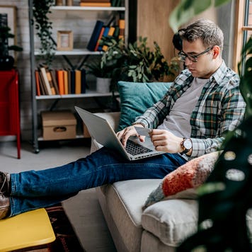 man using a laptop and credit card on the sofa at home