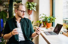 man looking at phone while having coffee in cafe