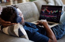 A trader lays back on a couch with his laptop computer