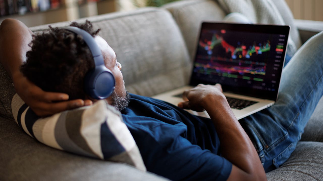 A trader lays back on a couch with his laptop computer