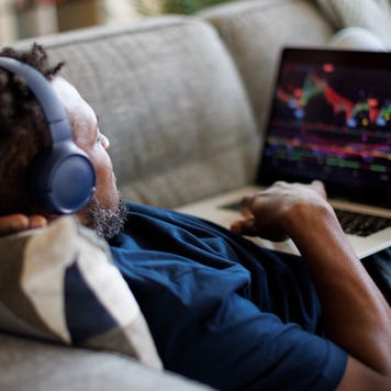A trader lays back on a couch with his laptop computer