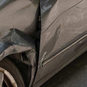 Close-up of a wrecked front quarter panel on the driver's side of a silver car