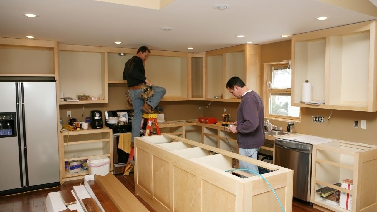 Contractors install new cabinets in a kitchen remodel
