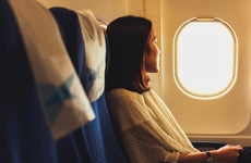 side view of woman looking out airplane window