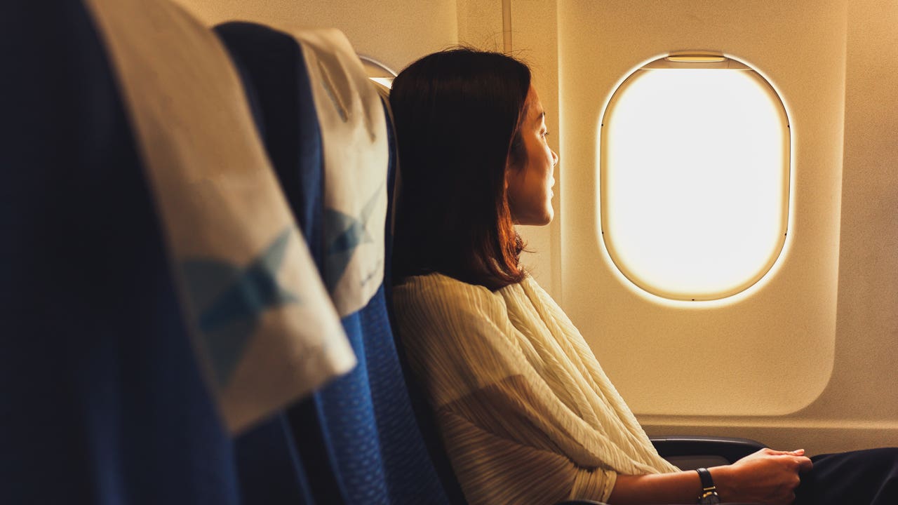 side view of woman looking out airplane window