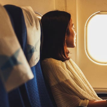 side view of woman looking out airplane window